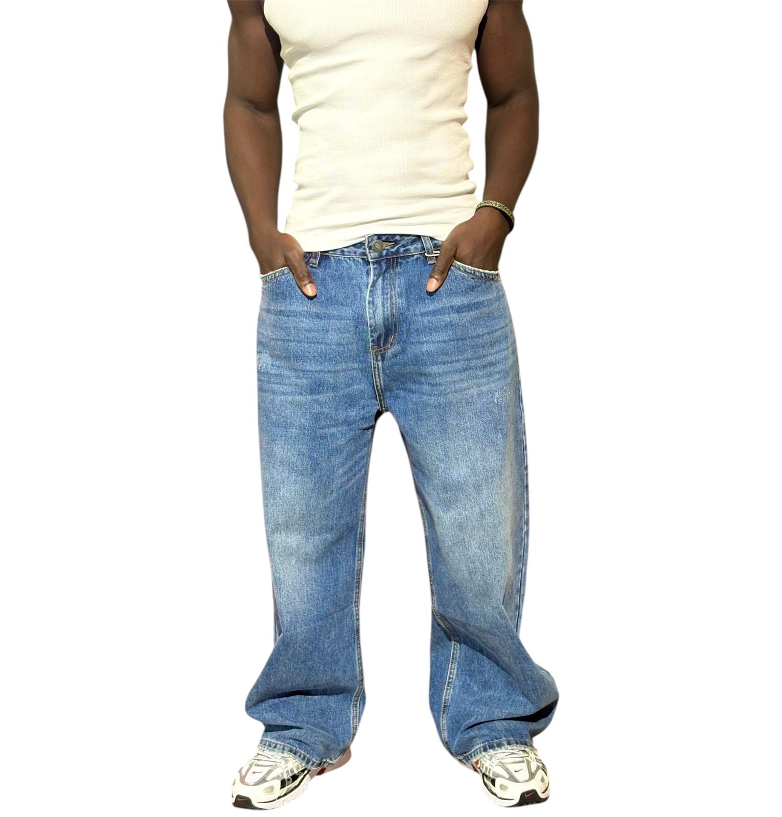 Person wearing blue jeans and a white tank top on a white background
