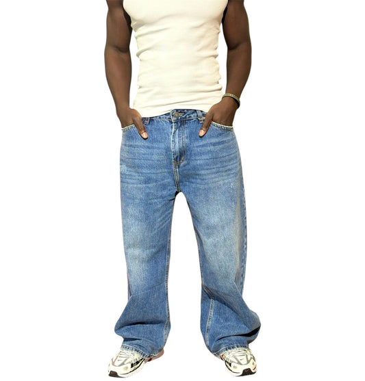 Person wearing blue jeans and a white tank top on a white background